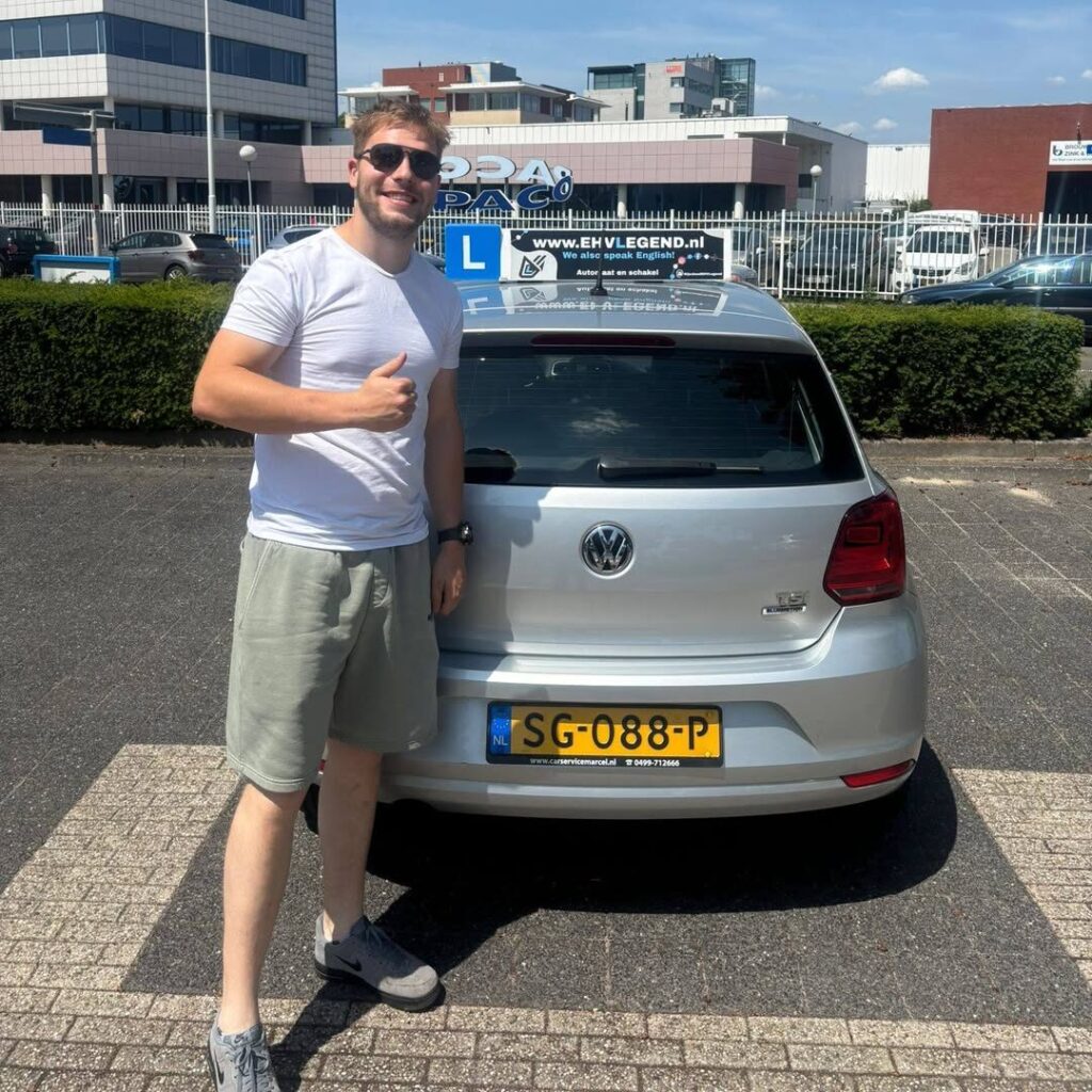 Geslaagde leerling toont duim omhoog naast lesauto van rijschool EHVLegend in Eindhoven Geslaagde leerling toont duim omhoog naast lesauto van rijschool EHVLegend in Eindhoven