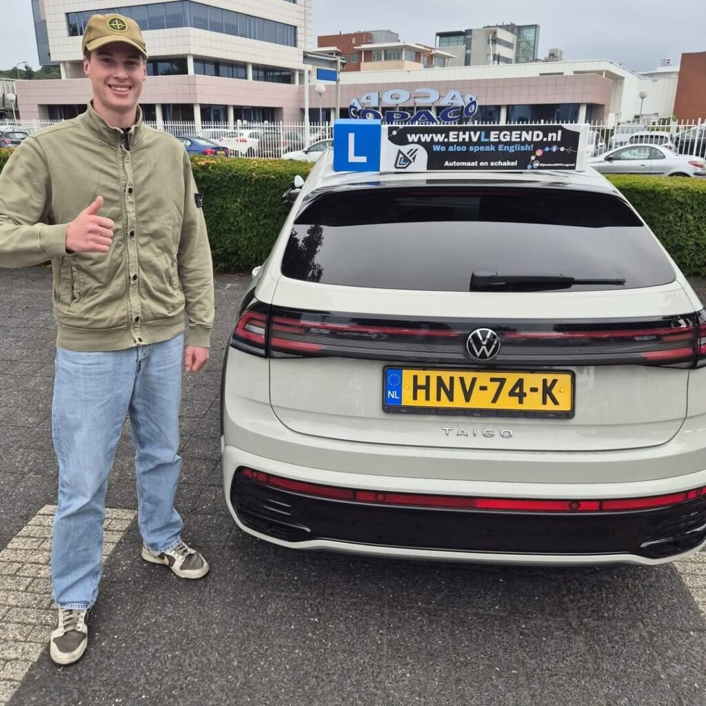 Geslaagde rijleerling van Rijschool EHVLegend poseert met duim omhoog naast lesauto in Eindhoven Geslaagde rijleerling van Rijschool EHVLegend poseert met duim omhoog naast lesauto in Eindhoven
