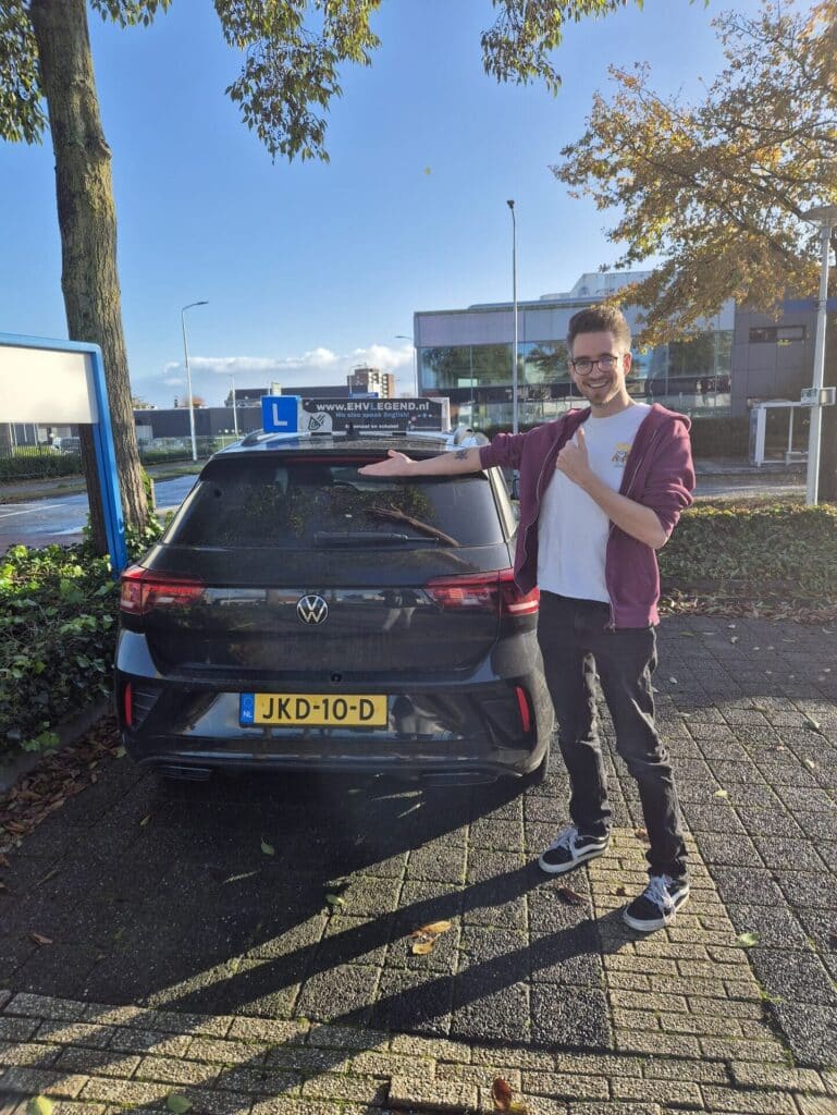 Geslaagde rijleerling van Rijschool EHVLegend poseert trots bij Volkswagen lesauto na het behalen van rijbewijs Geslaagde rijleerling van Rijschool EHVLegend poseert trots bij Volkswagen lesauto na het behalen van rijbewijs